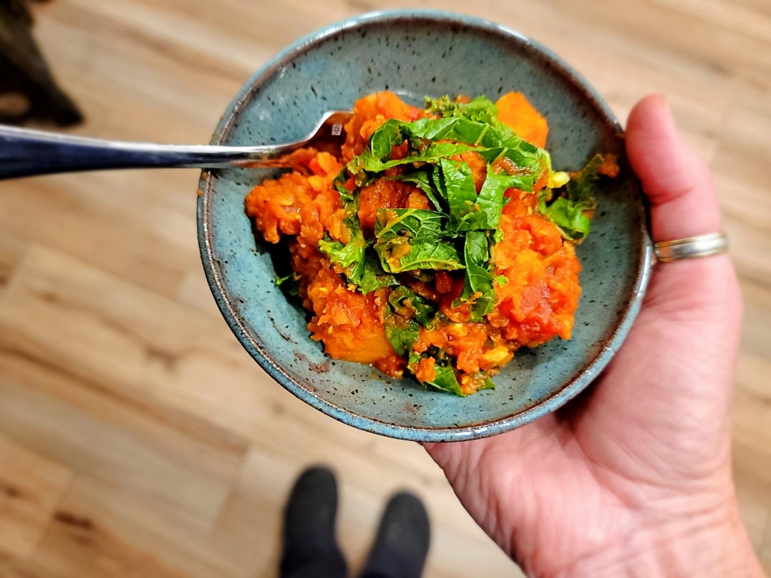 Butternut & Red Lentil Curry in bowl + chef hand + spoon