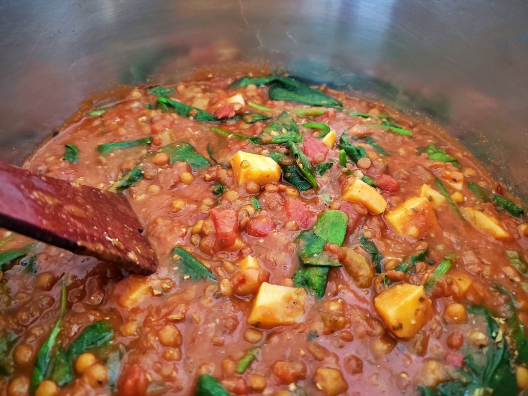 Tuscan Lentils Potatoes & Spinach in saucepan with a spoon