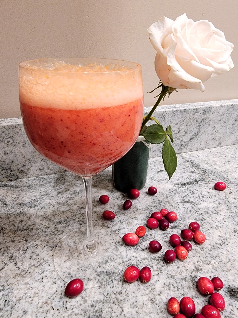 Cranberry, Orange, Ginger Fizz in a wine glass + fresh cranberries + white rose stem